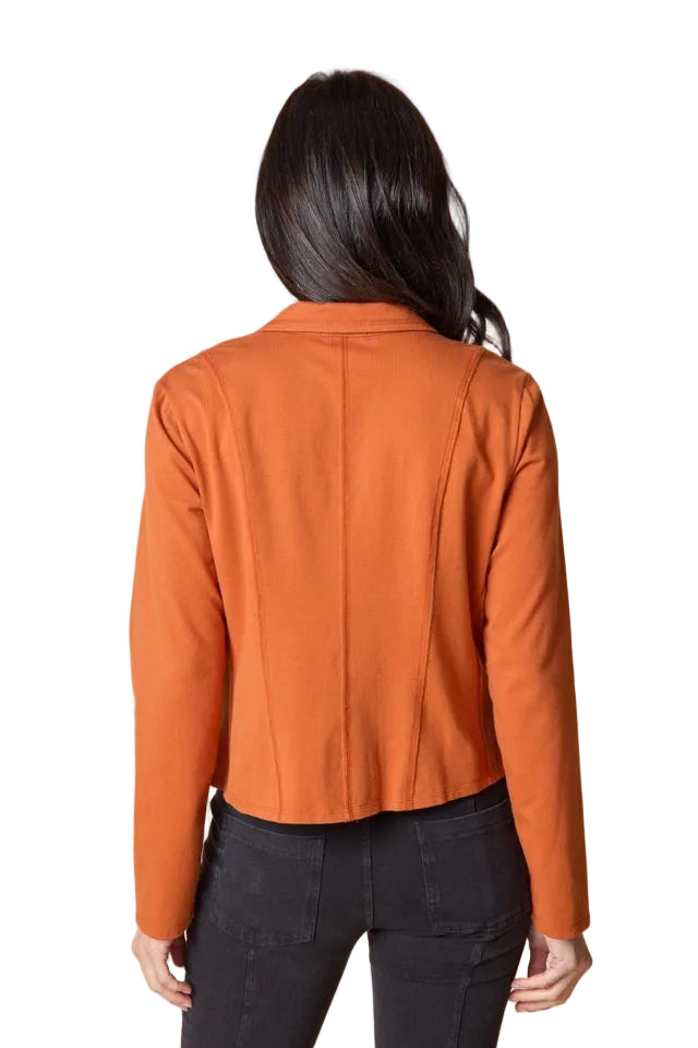 Woman wearing an orange jacket against a beige background