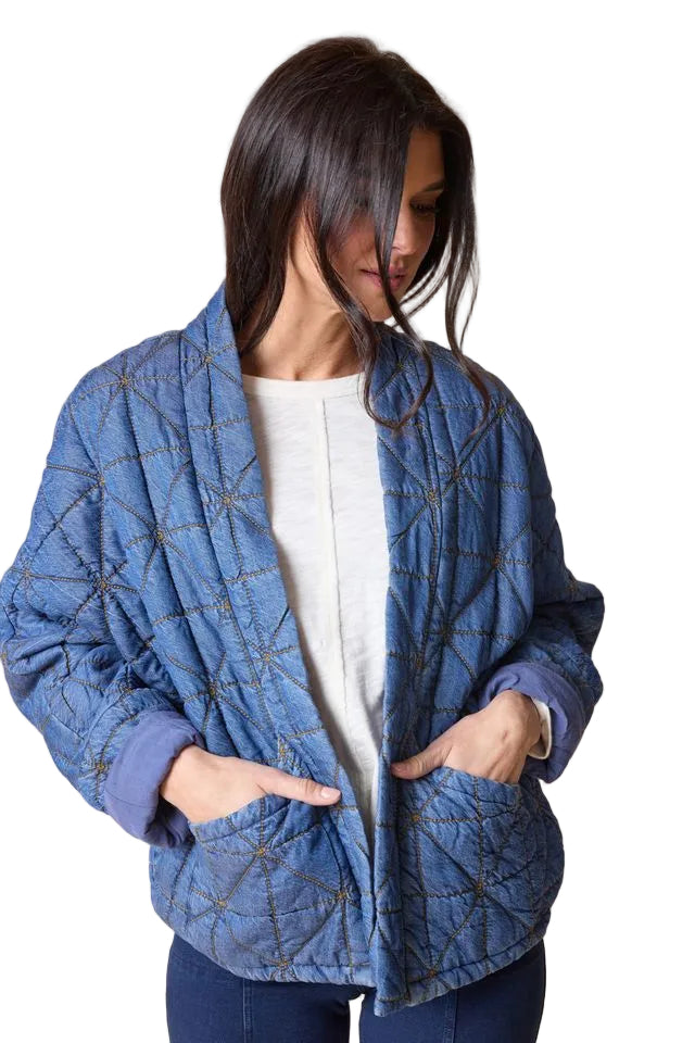 Woman wearing a blue quilted jacket on a beige background