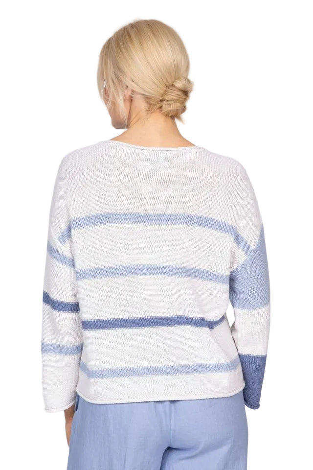 Woman wearing a striped sweater and pants on a plain background